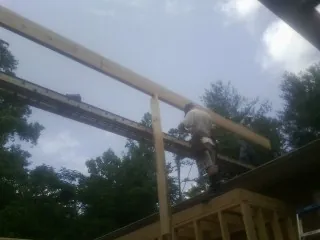 Carpenter setting a ridge beam over a new addition frame — Ice Dam Removal by Roofing Brothers in Swartz Creek