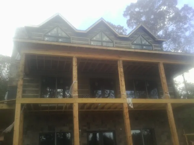 Dormers and porch framing on a large log home under construction — Roof Coating work by our crew in Swartz Creek